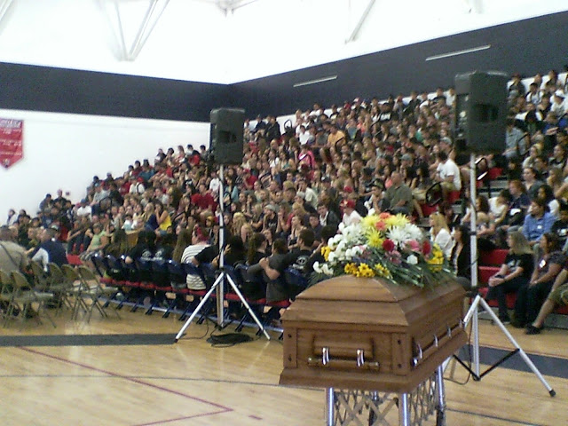 coffin with flowers on top of it in front of a group of students