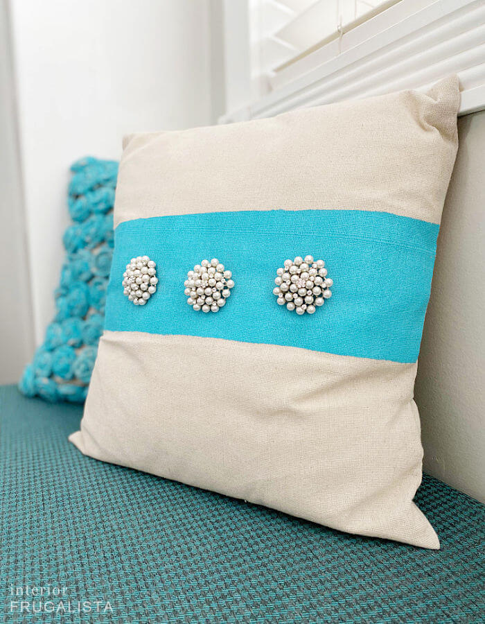 A handmade envelope pillow embellished with a strand of vintage pearl earrings.