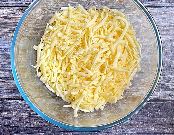 Grated cheddar and mozzarella in a glass bowl.
