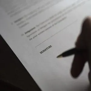 Foto imagem de parte de um contrato de locação residencial sendo assinado.