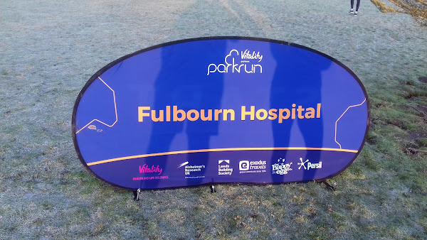 A sign for Fulbourn Hospital parkrun on some frosty grass
