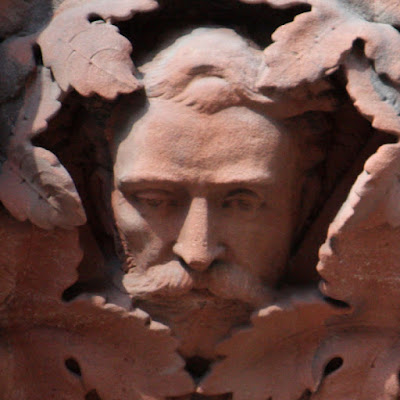 Detailed carving in red sandstone of a man's head surrounded by leaves