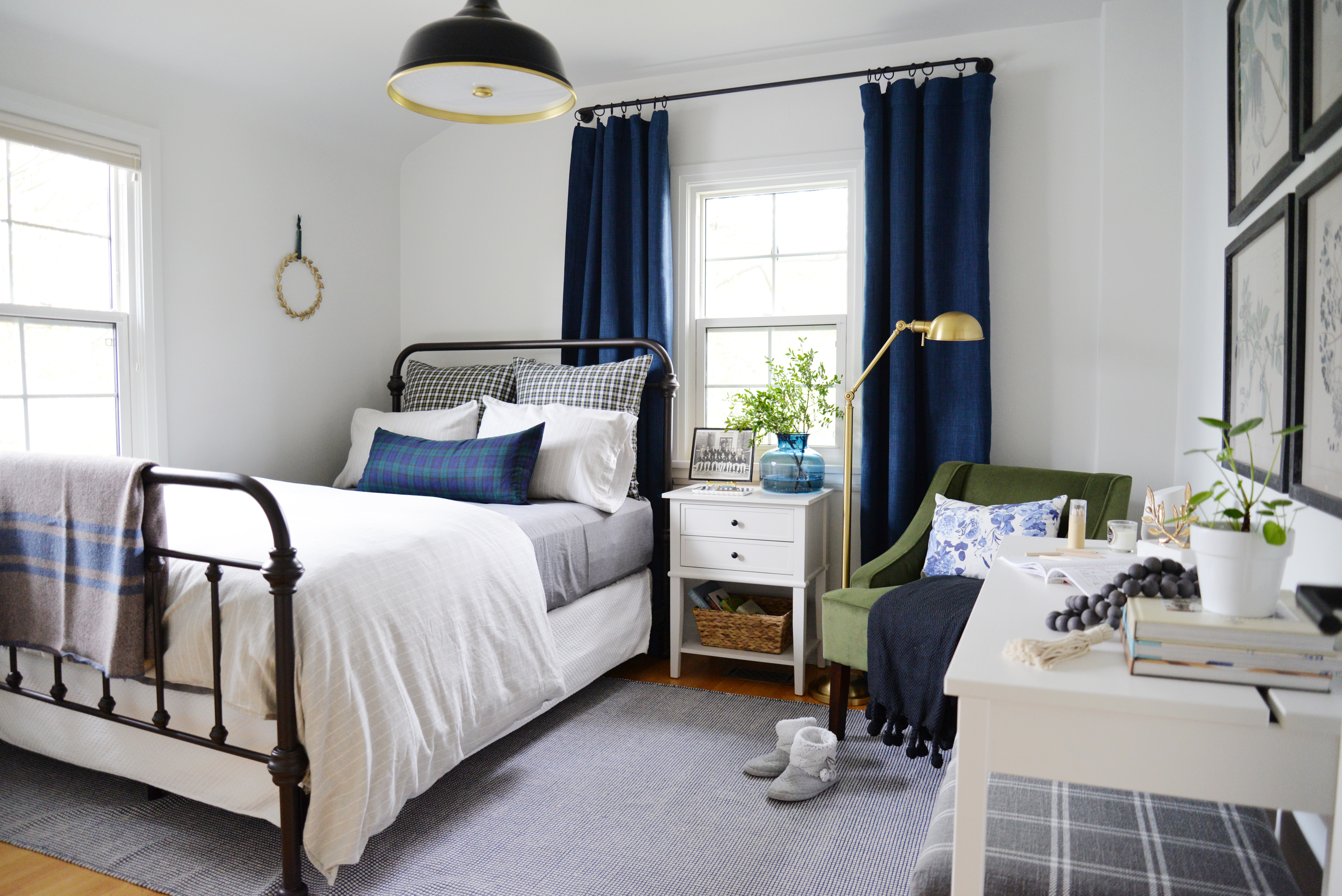 guest bedroom with metal bed, white walls, and navy blackout curtains