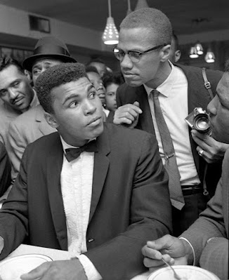 Malcolm X leaning on Cassius Clay (Muhammad Ali) at victory party after he defeated Sonny Liston for the Heavyweight Championship, February, 1964