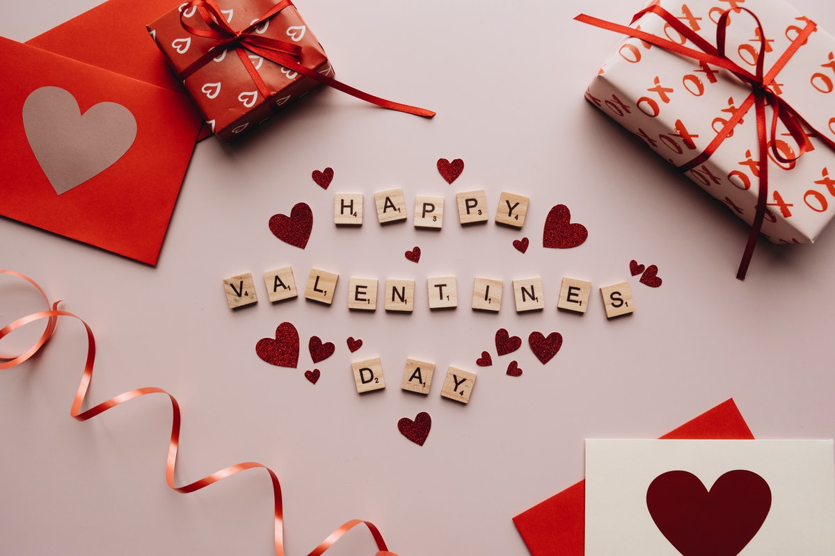 Happy valentine’s day text with some wrapped gifts and cards in red and white