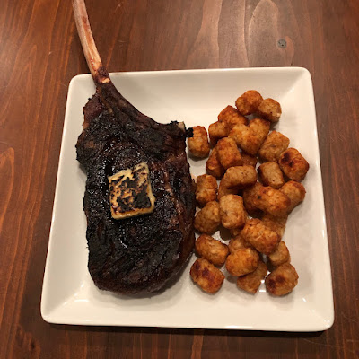 Tomahawk and tots, a rare grilled bison tomahawk ribeye topped with melted bleu cheese, along with some tater tots