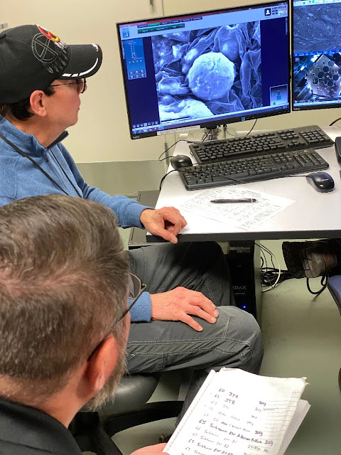 El estudiante de antropología de la Universidad de Cincinnati Louis Herzner, abajo, y el profesor de antropología Kenneth Tankersley utilizan un microscopio electrónico de barrido en el Centro de Caracterización de Materiales Avanzados de la UC para estudiar las microesferas ricas en hierro y silicio recogidas en antiguos yacimientos de Hopewell. Foto/Larry Sandman