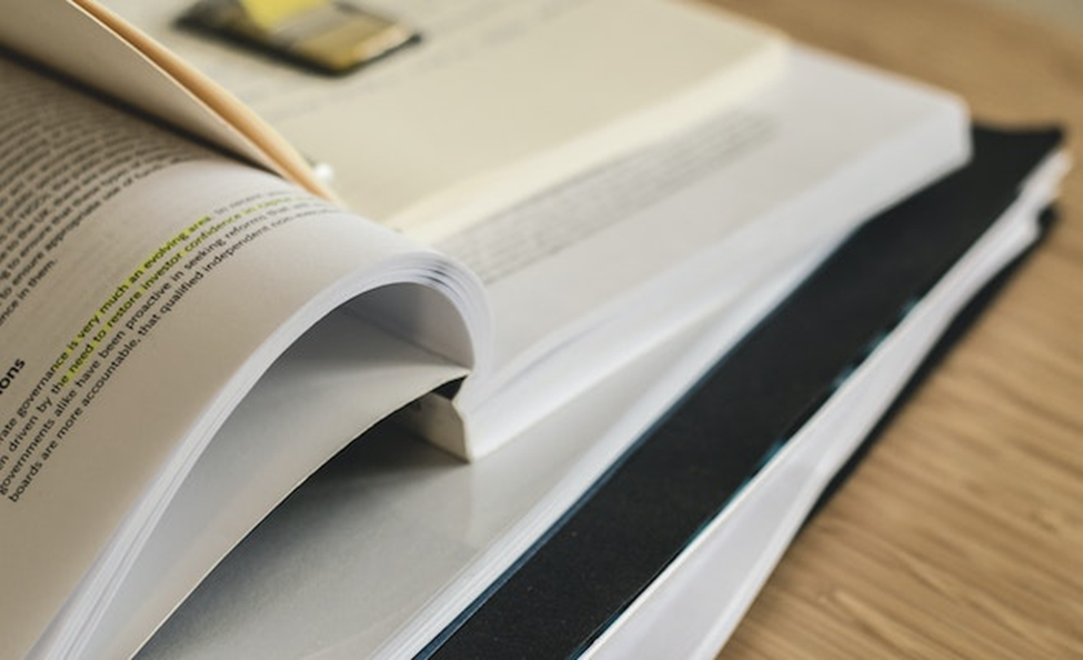 Image of open books laid on top of one another on a desk.