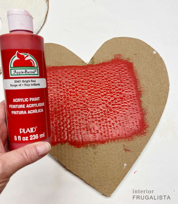 Painting the inside bottom piece of a handmade heart wreath form bright red.