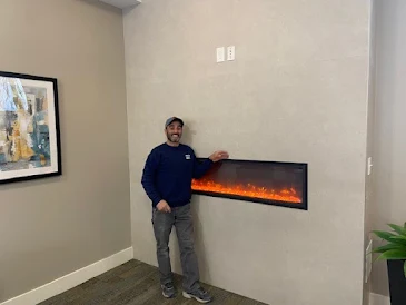 Manny Costa, maintenance tech, standing next to a fireplace