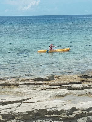 Tourist kayaking along circumference of tiny " Schooner Island " .