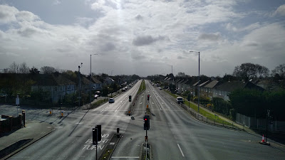 A view of a large trunk road junction taken from a bridge. Apart from a couple of cars, it is completely empty.