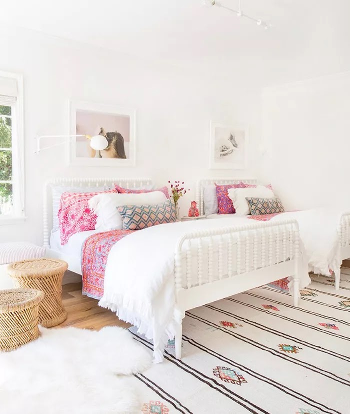 Duvarda pembe desenli ve sanat eseri olan iki beyaz yataklı ortak bir genç kız yatak odası.