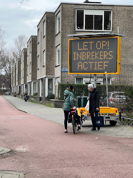 Mensen in gesprek voor een matrixbord met de tekst 'Let op! Inbrekers actief'