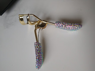 Gold eyelash curler white rhinestone encrusted handles.