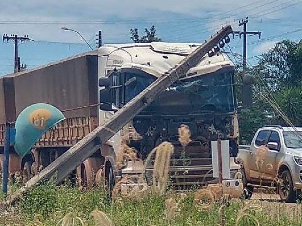 Carroceria de caminhão enrosca em fios e derruba poste em cima de cabine de carreta estacionada