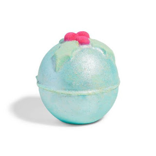 A spherical silver lustre coated bath bomb with a hexagonal bottom with lush engraved into it with a 3d red spherical holly berries and green holly leaf on top on a bright background
