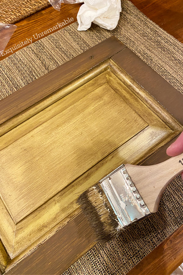 Brushing dark stain onto outer moulding of cabinet door