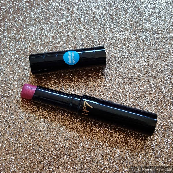 limited edition pink lipstick in black case with swirl pattern on lid on glitter background