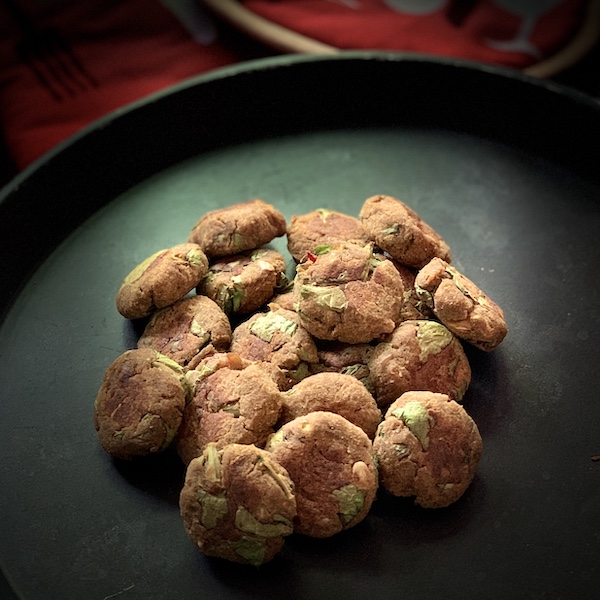 Dark background, black tray with small, bite sized patties on it.