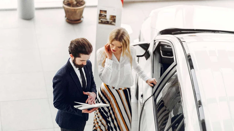 A salesperson and a customer discuss a car.