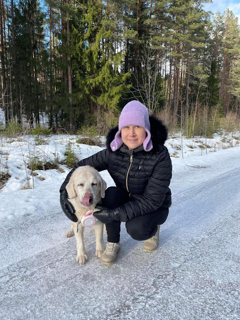 Kai kükitab koos oma pensionärist juhtkoeraga lumisel talveteel. Tabatud on kelmikas hetk sellest, kus kollane labrador Janet limpsab keelega oma nina. Kail on seljas mustad liibuvad teksad, must kapuutsiga jope, mille kaelusest paistab hall kapuutsiga dressikas, peas lapatsitega udupehme roosa müts.