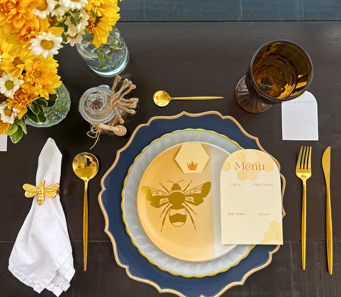 Thanksgiving dinner table setting, fall, autumn, yellow flowers, daisies, golden bee napkin ring, golden cutlery, plates, menu, place, gratitude cards, crystal glass, honeycore aesthetic, honey pot