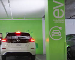 Nissan Leaf parked at a charging station with a green fully charged indicator