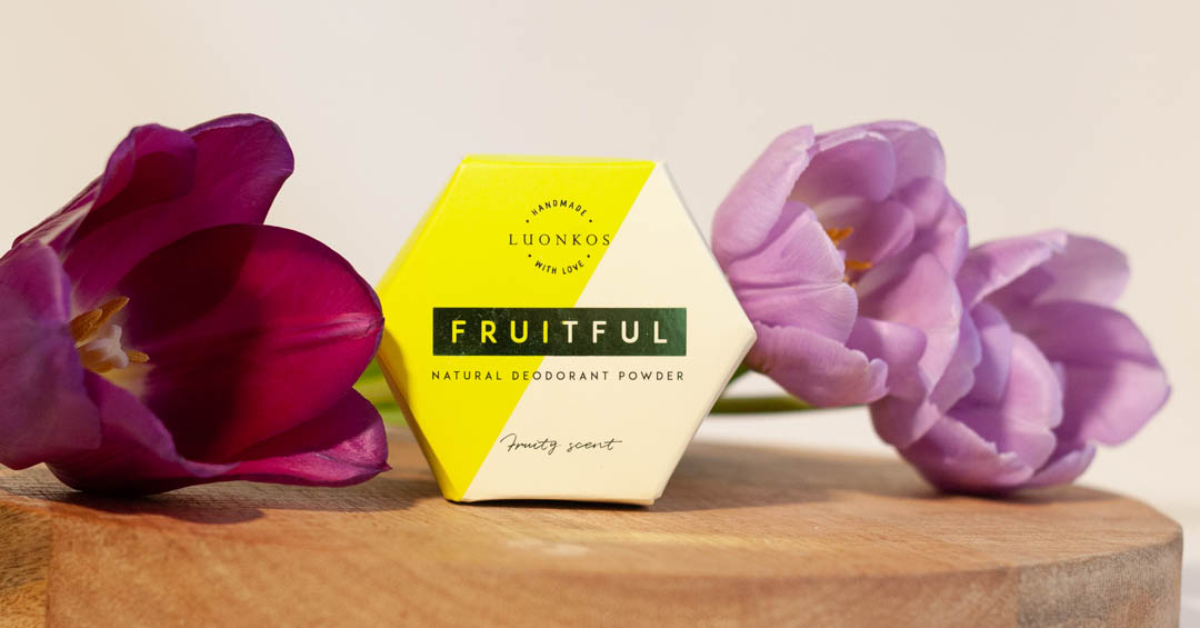 Luonkos Fruitful jauhedeodorantti puukiekon päällä violettejen tulppaanien kanssa