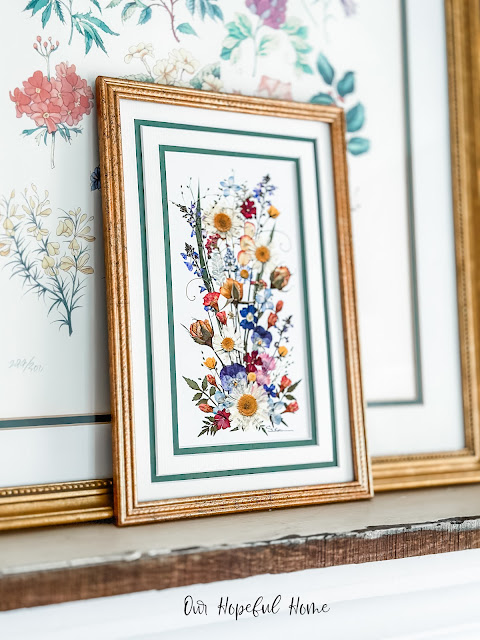 gold framed pressed flower print leaning on floral artwork