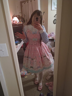 Me wearing the pink Marshmallow Bunny Ribbon JSK by Angelic Pretty on top of a blue and white striped blouse with a white yolk. Pink shoes and white socks. I'm waving.