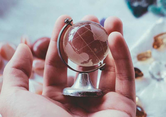 a small globe of the earth being held gently in a person's hand