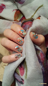 Nageldesign: Blau-orange lakiert, bestreut mit Glitzersteinchen und Blumenaufklebern