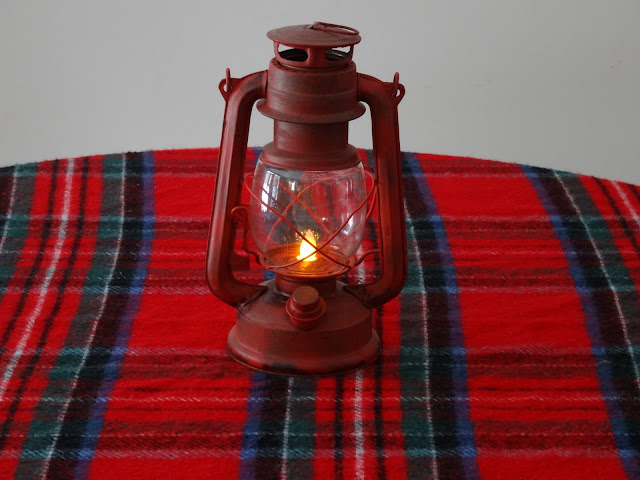 A red plaid scarf with faux lantern on the kitchen table. 