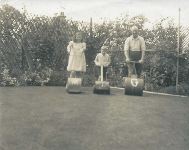 Grandad Beck with Grandchildren lining up for a race. Marion has a lawnmower with a M on it. Jackson has a lawnmower with J on it and Grandad has a lawn roller with G.