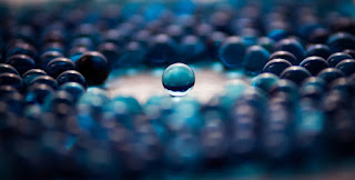 A group of blue marbles, in which one stands apart in the centre.