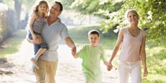 Family walking outdoors holding hands and smiling