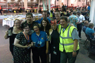 Group shot of nine people at Olympia raising a glass (or tankard) to my leaving.