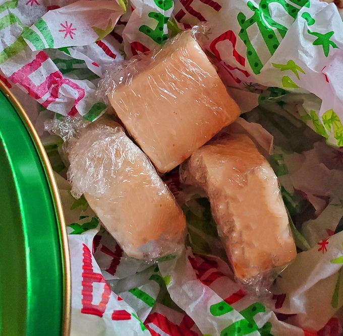 peanut butter 4 ingredient fudge wrapped in plastic in a pretty Christmas tin