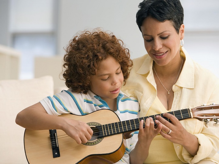 Child Learning How to Play the Guitar