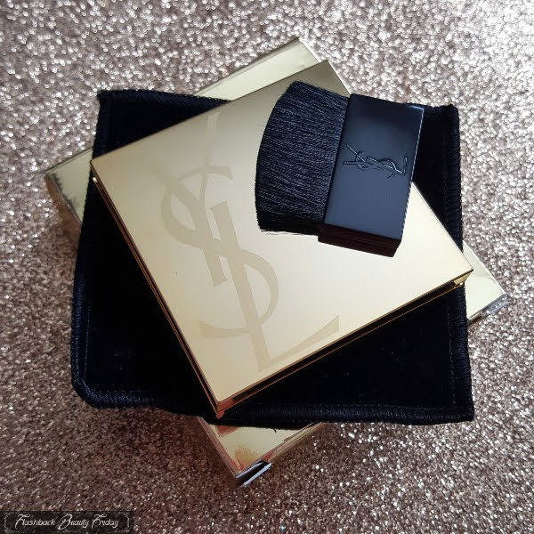 gold YSL compact on top of black velvet pouch with YSL face brush on top