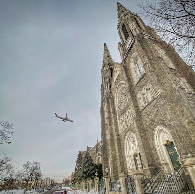 The outside of St. Patrick's Church, with a plane landing in the background