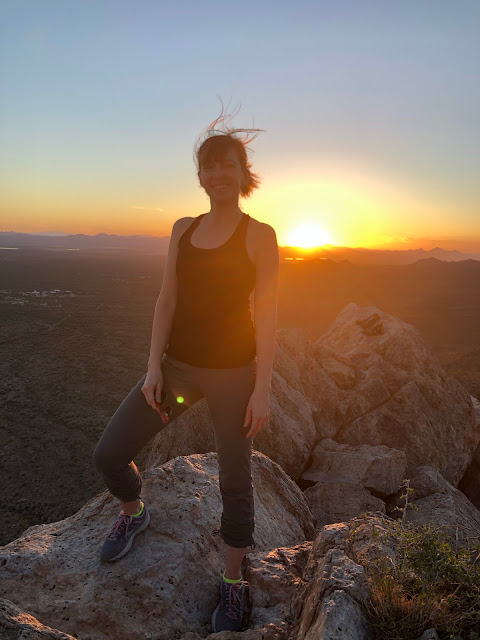 woman standing atop a mountain at sunset