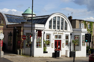 A white-painted building with a cross-shaped, curved glass roof.