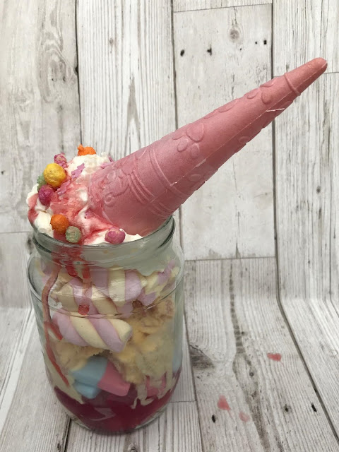 Unicorn sundaes made with sweets and ice cream and a pink cone for a horn