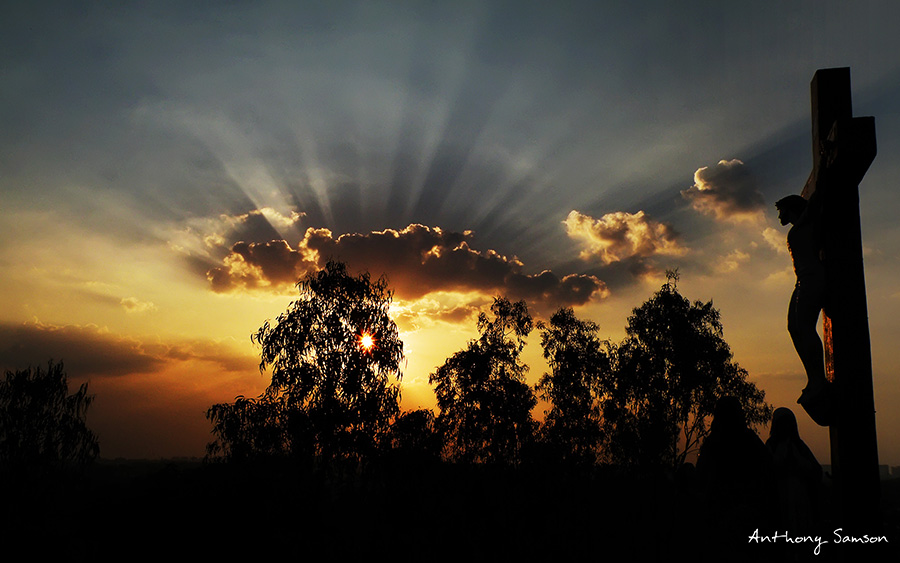 Sunset photo with statue of jesus on cross as a silhoute