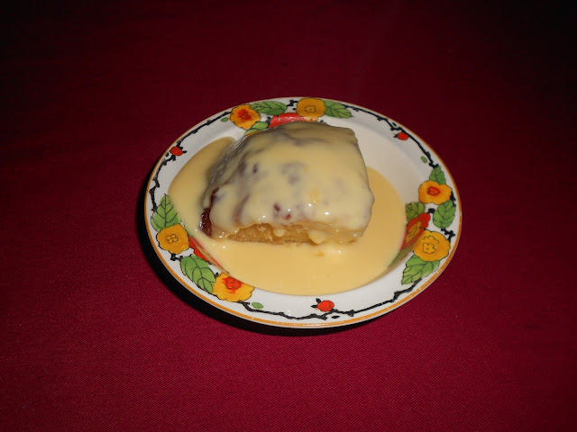 A vintage plate showing a slice of jam steamed pudding and custard