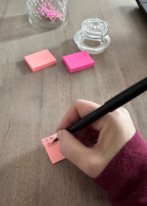 Writing on a colorful post it note.