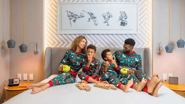 A family in bed eating and wearing holiday-themed Nickelodeon pajamas