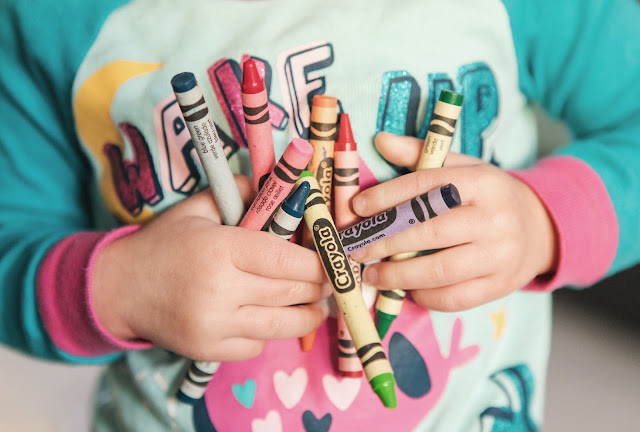 toddler holding lots of crayons:Photo by Kristin Brown on Unsplash